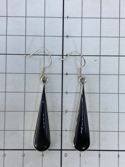 Aretes con onix en mano, mostrando proporción y brillo de la plata