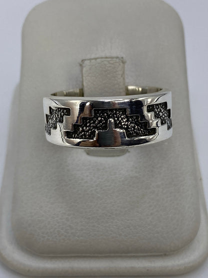Anillo de plata repujado con motivos prehispánicos, vista frontal en dedo