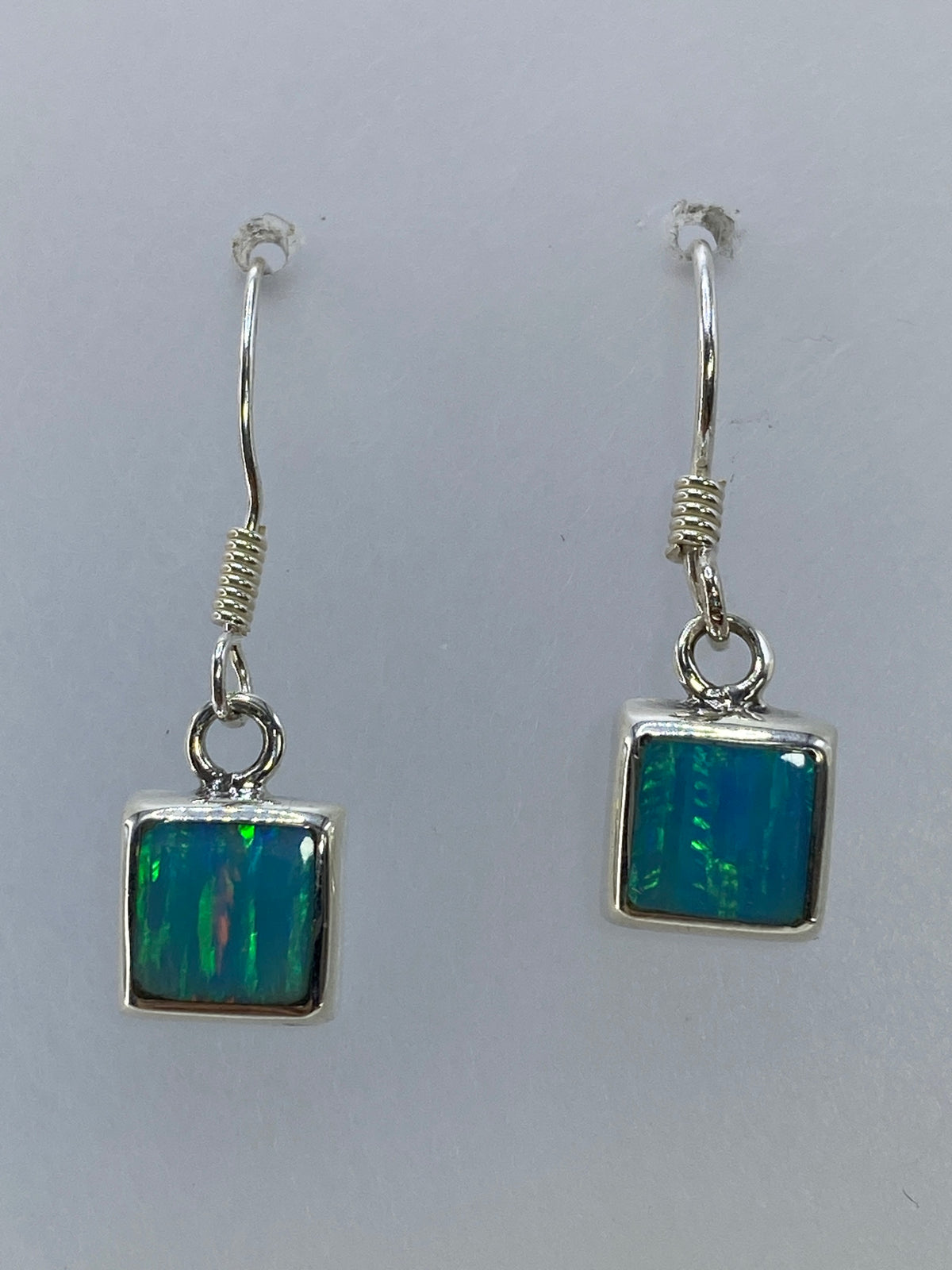 Par de aretes de plata 925 con ópalo de fuego multicolor colgando de un gancho de plata