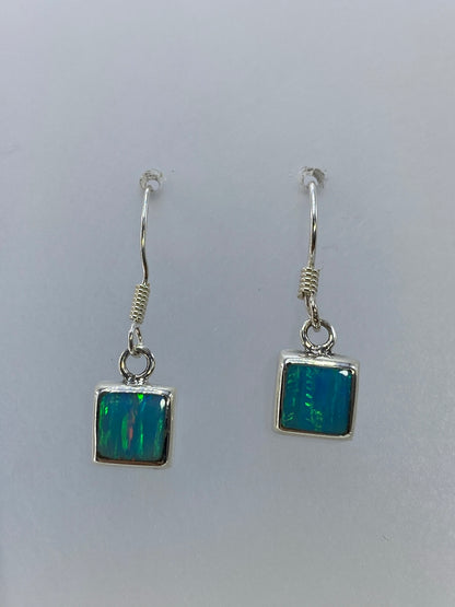 Aretes de plata con ópalo de fuego mostrando los tonos naranjas, rojos y verdes de la piedra