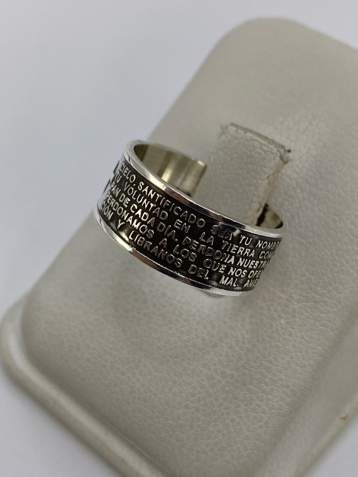 Anillo de plata religiosa puesto en dedo, mostrando el grabado completo