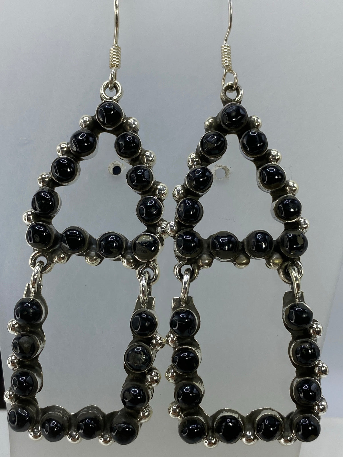Aretes de onix y plata Taxco colgando, mostrando la elegancia del largo de 7 cm