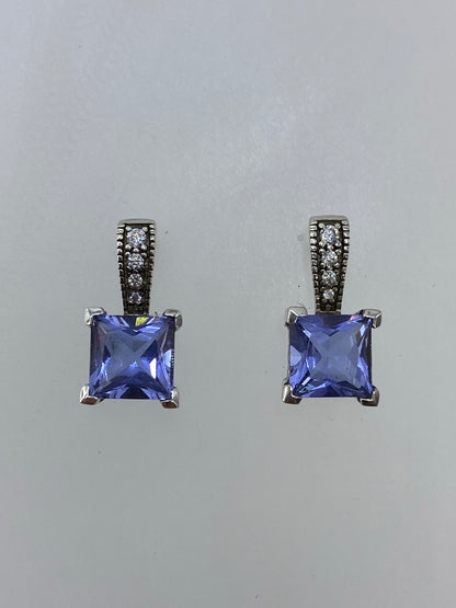 Par de aretes de plata 925 con circonia morada cuadrada, facetados, sobre fondo blanco