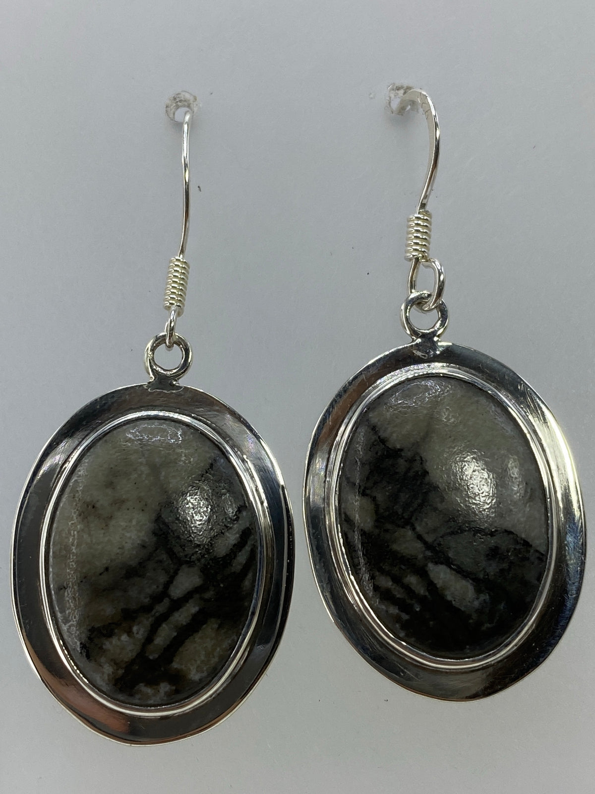 Detalle del engaste de piedra multicolor en plata, visto de cerca en los aretes