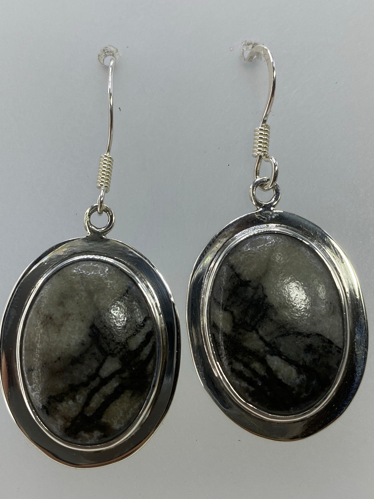 Aretes puestos en oreja mostrando el tamaño y el movimiento de la piedra multicolor
