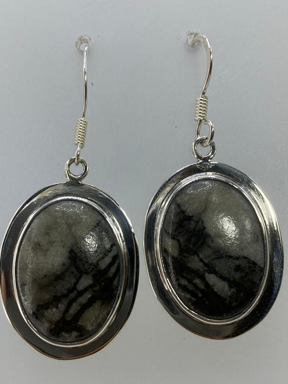 Aretes puestos en oreja mostrando el tamaño y el movimiento de la piedra multicolor