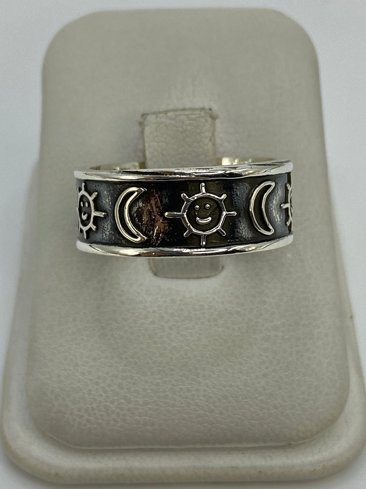Anillo de plata 925 repujado con sol, lunas y estrellas en relieve, sobre anillo de presentación blanco