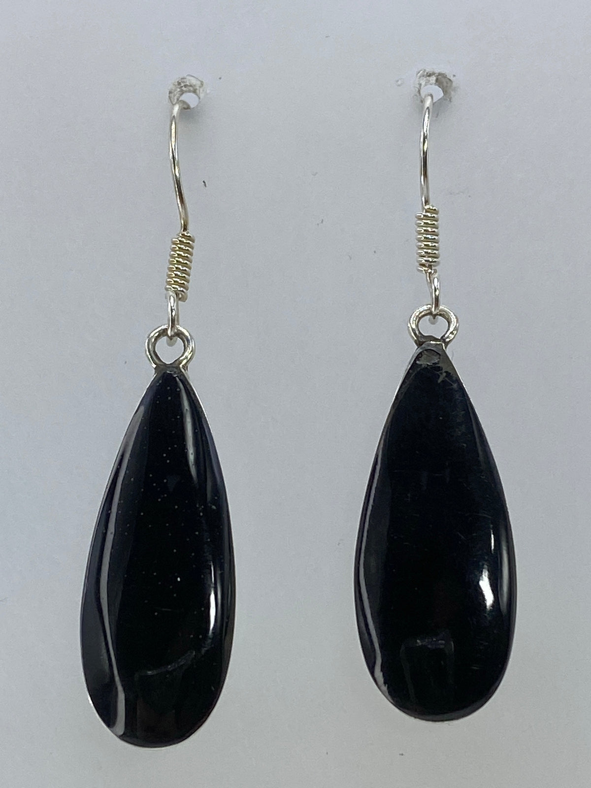 Par de aretes de plata en forma de gota con piedra negra, vistos de frente