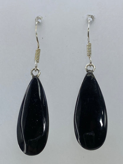 Par de aretes de plata en forma de gota con piedra negra, vistos de frente