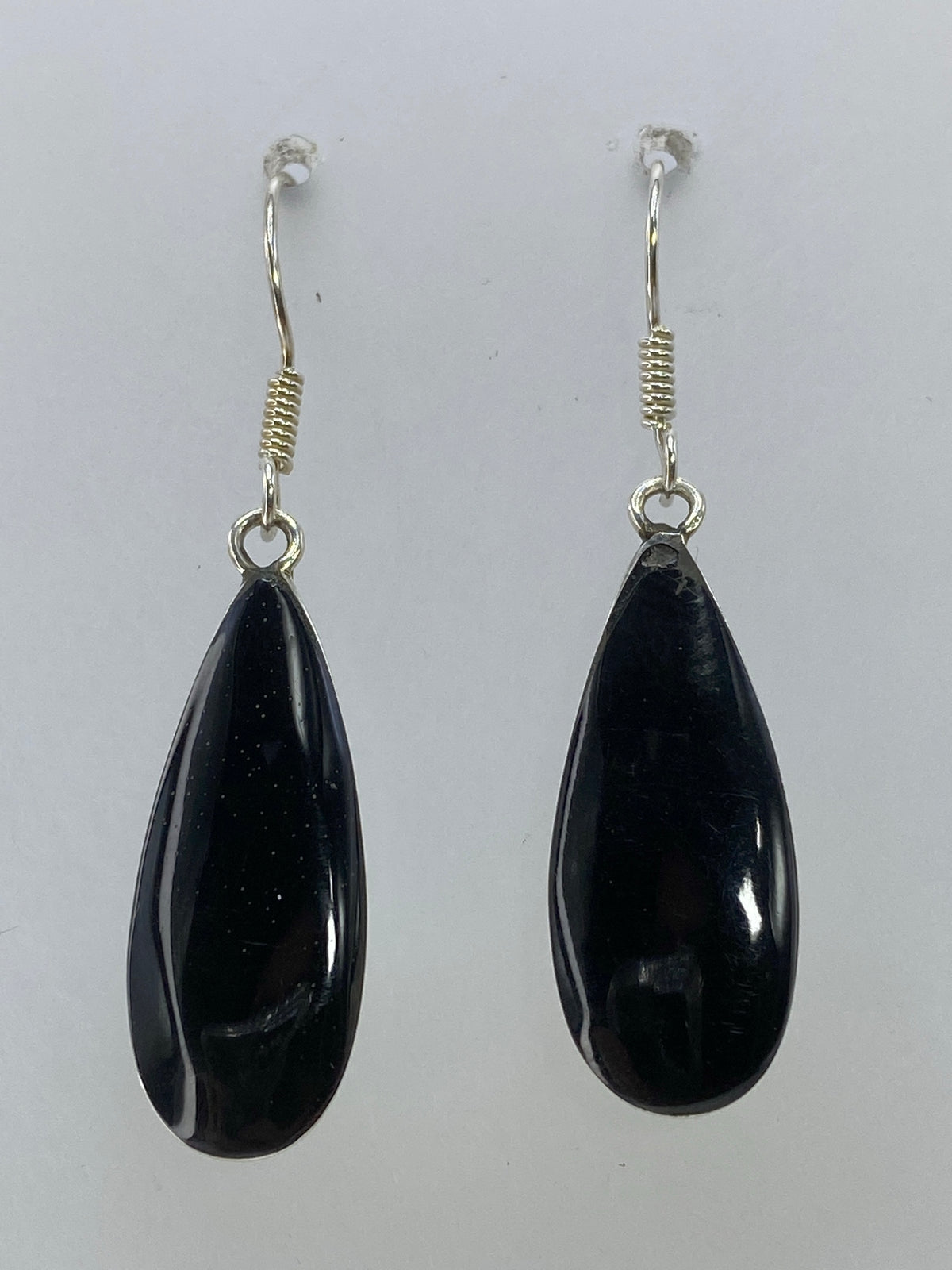 Aretes de plata gota negra sobre fondo blanco mostrando el Quinto 925