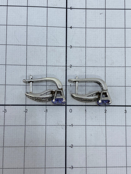 Aretes de circonia morada sobre fondo neutro, mostrando el sello 925