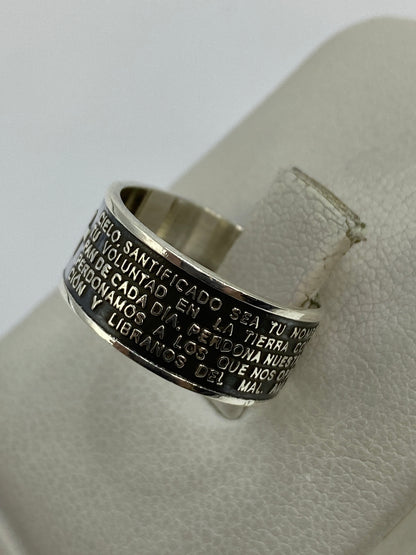 Anillo religioso de plata colocado en dedo, mostrando la legibilidad del texto