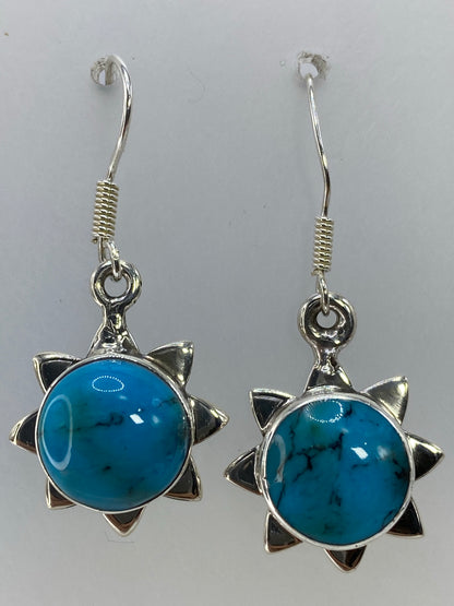 Aretes sol de plata posados sobre fondo blanco con el Quinto 925 visible