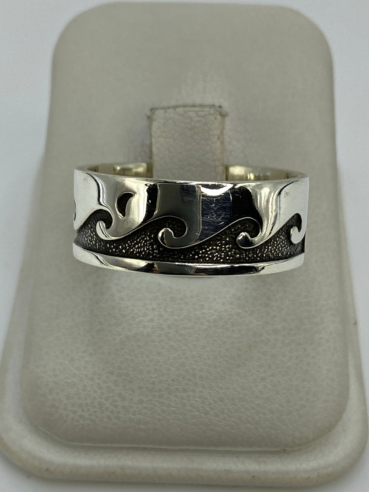 Anillo de plata repujado ancho, visto desde arriba, en la mano mostrando el relieve textured