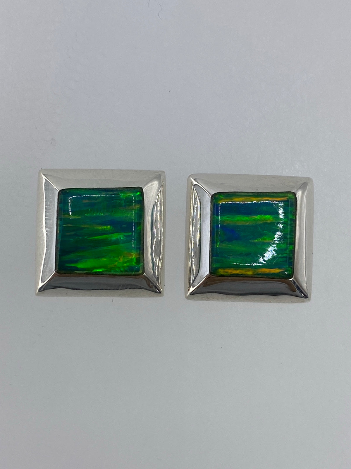 Par de aretes de plata con circonia multicolor engastada, colgando sobre fondo blanco