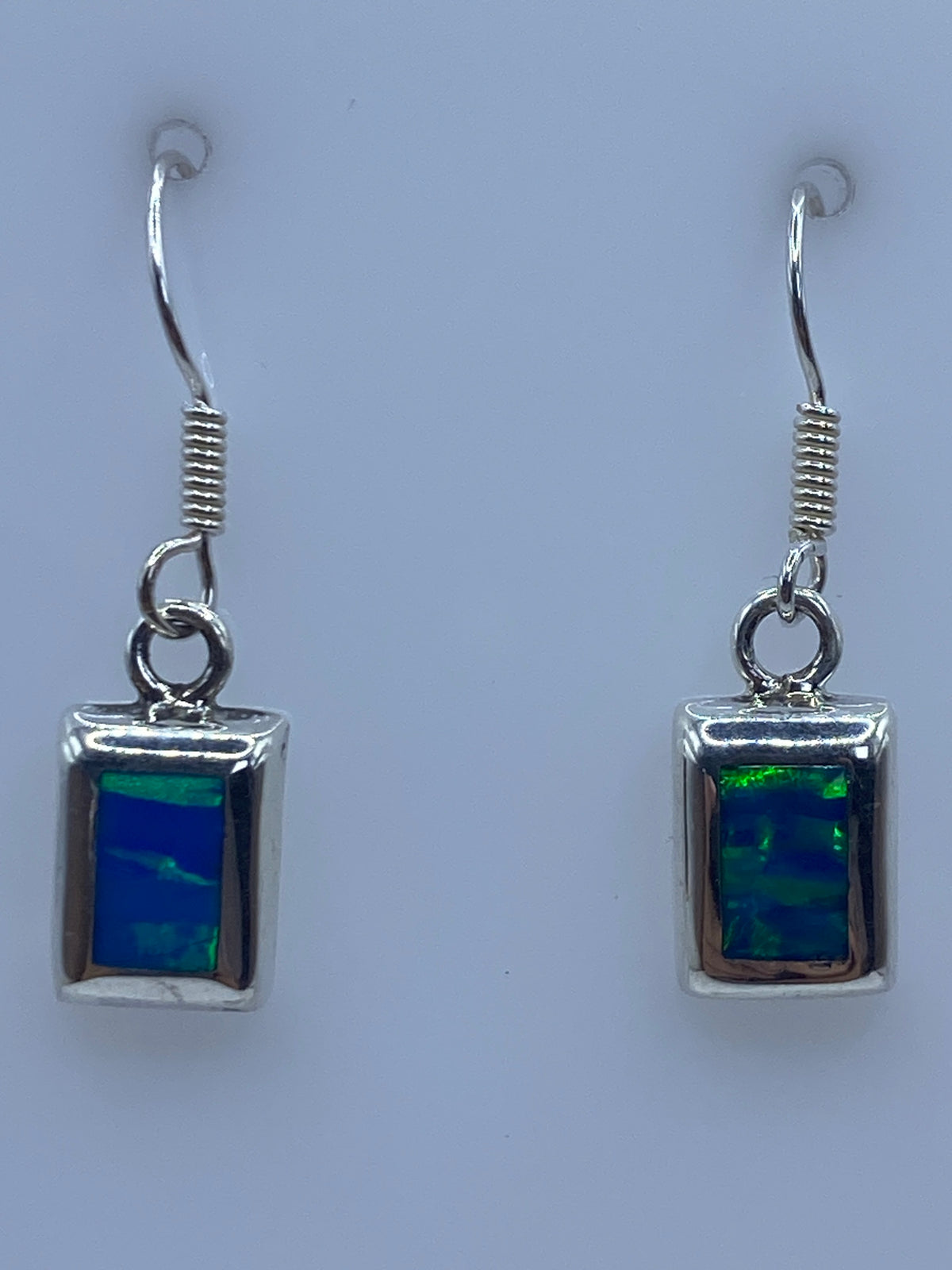 Par de aretes de plata 925 con ópalo de fuego azul engastado, sobre fondo claro
