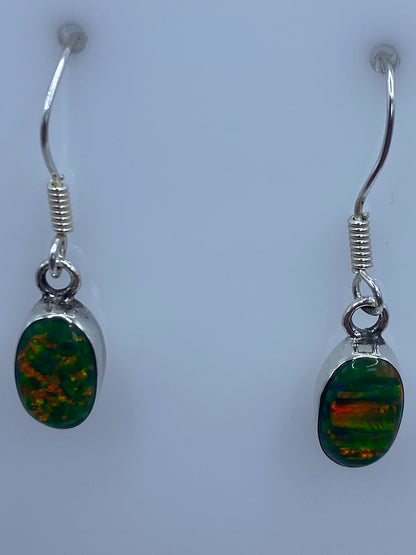 Detalle de un arete mostrando el engaste a mano del ópalo de fuego con tonos verde limón