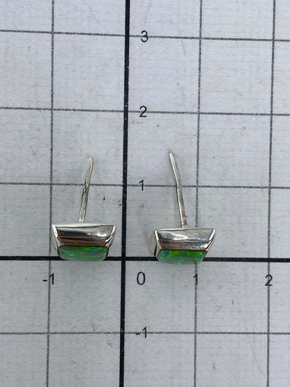 Ópalo de fuego verde limón reflejando luz en los aretes de plata