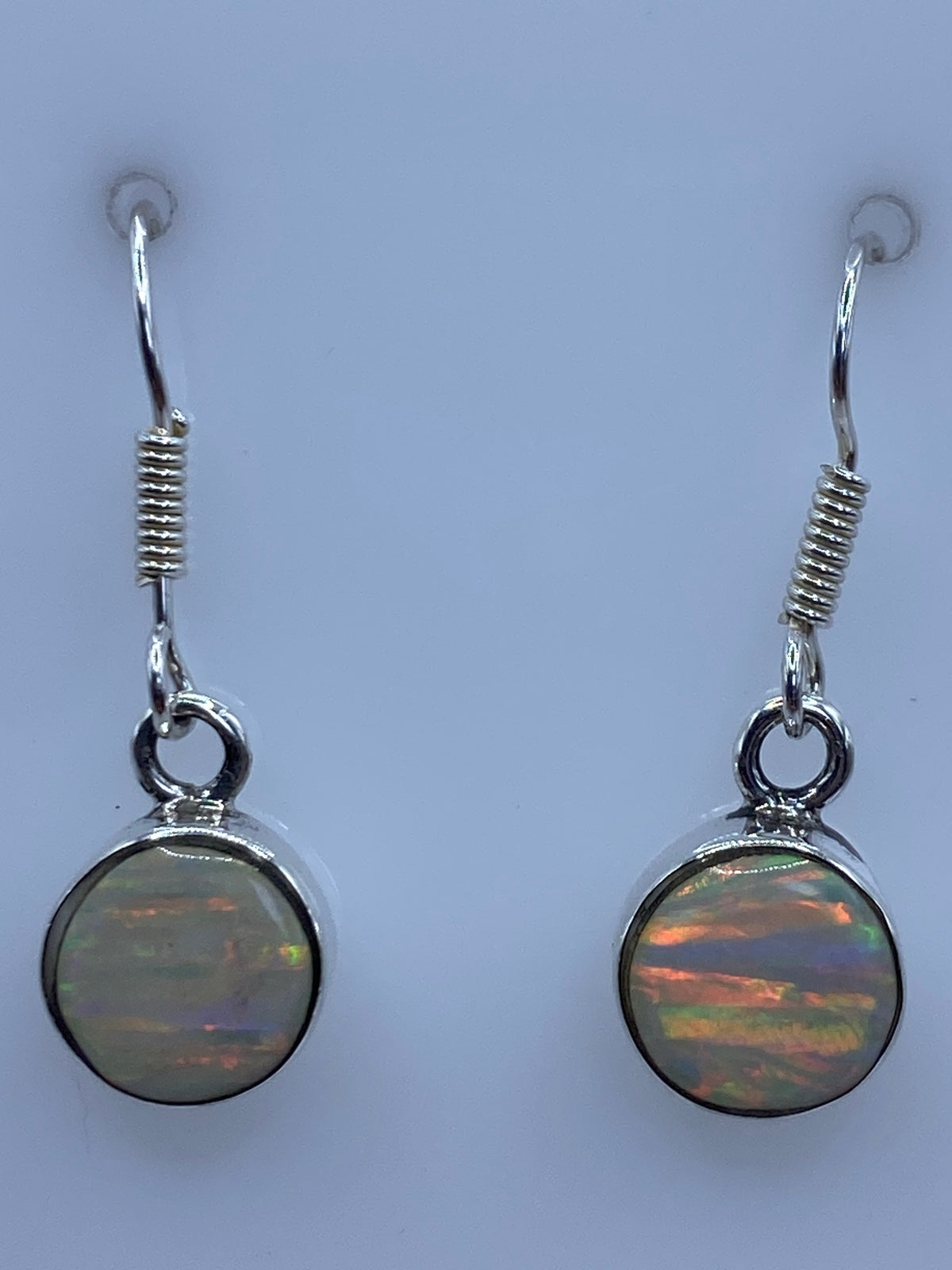 Aretes de ópalo sobre fondo neutro mostrando el largo de 2.5 cm