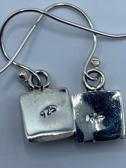 Aretes sobre fondo neutro: el ópalo de fuego multicolor reflejando luz dorada y roja