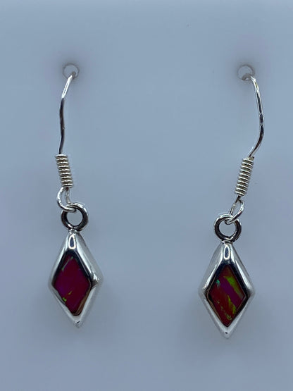 Par de aretes de plata con Opalo de Fuego rosa y dorado colgando sobre fondo blanco