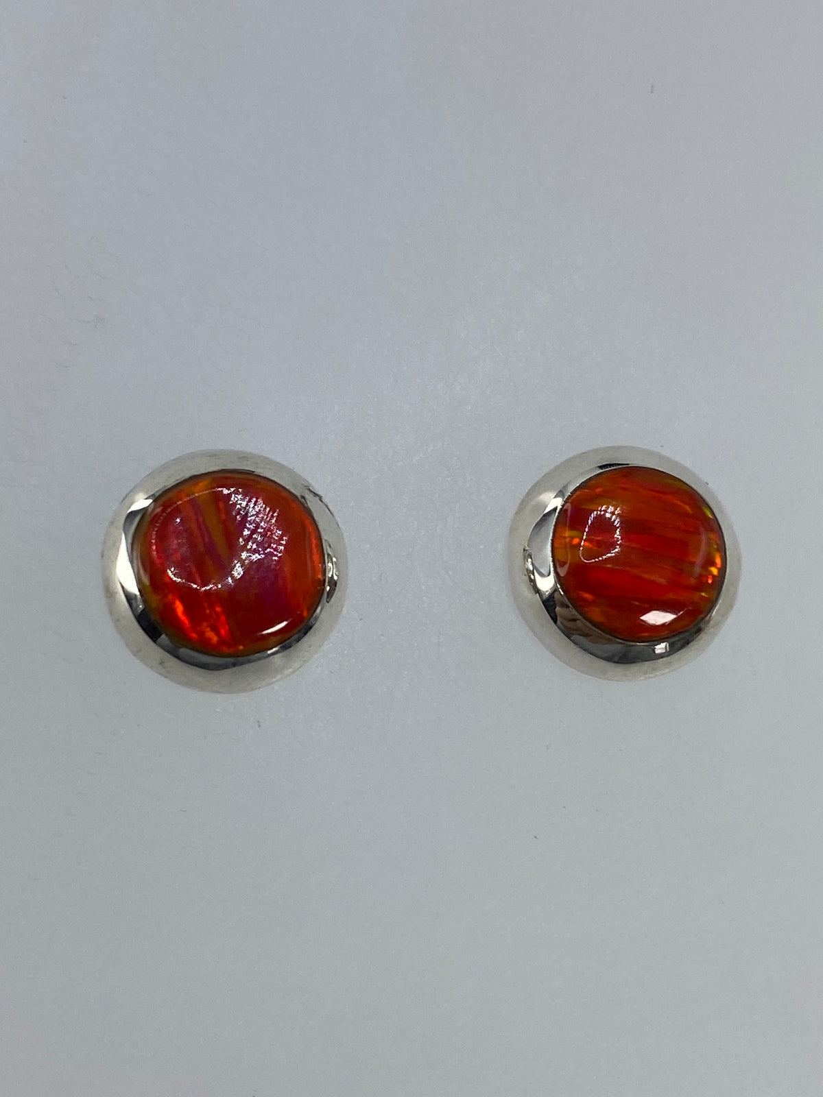 Aretes de plata con ópalo de fuego junto a moneda para escala de tamaño — 1.2 cm de largo