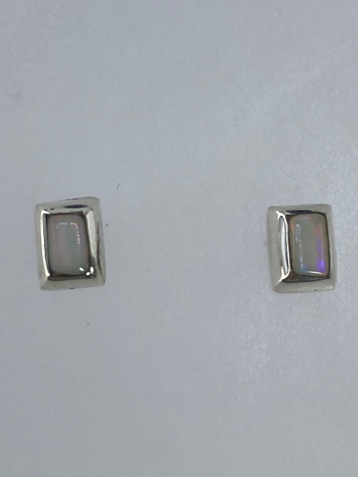 Par de aretes de plata con opalo de fuego multicolor, vista frontal sobre fondo gris