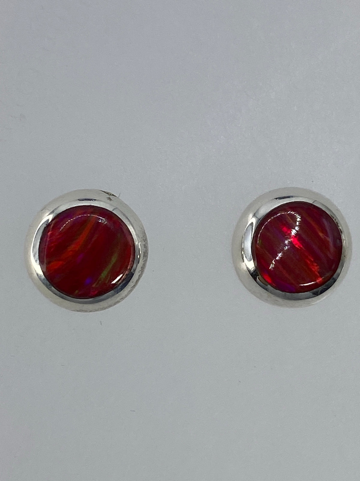 Par de aretes de plata con ópalo de fuego rojo brillante en posición frontal