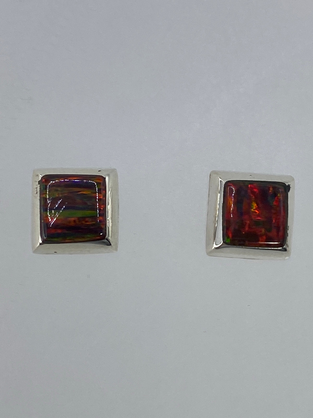 Par de aretes de plata con ópalo de fuego multicolor brillando en tonos rojos y naranjas
