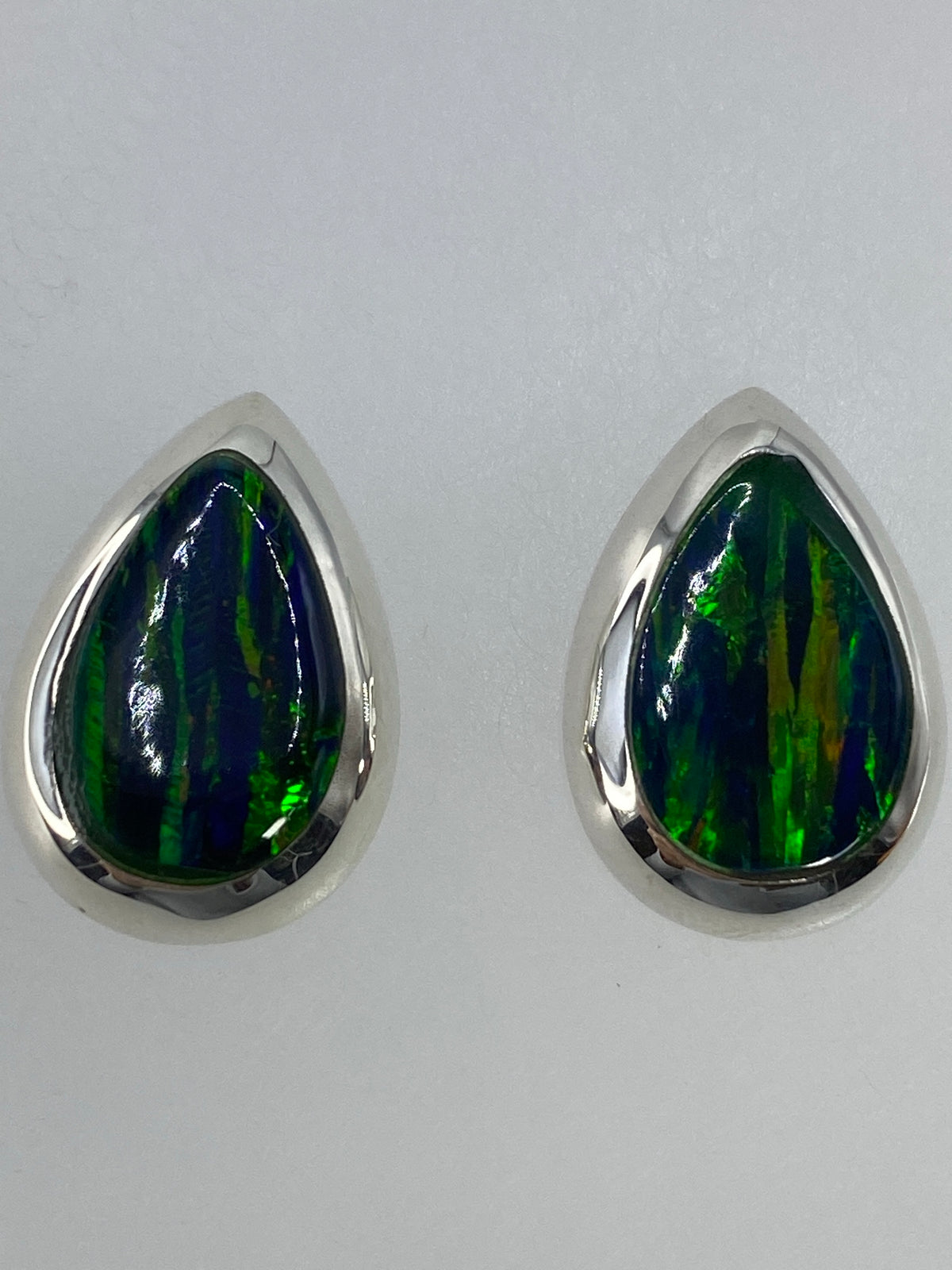 Vista frontal del par de aretes mostrando el color verde profundo del ópalo