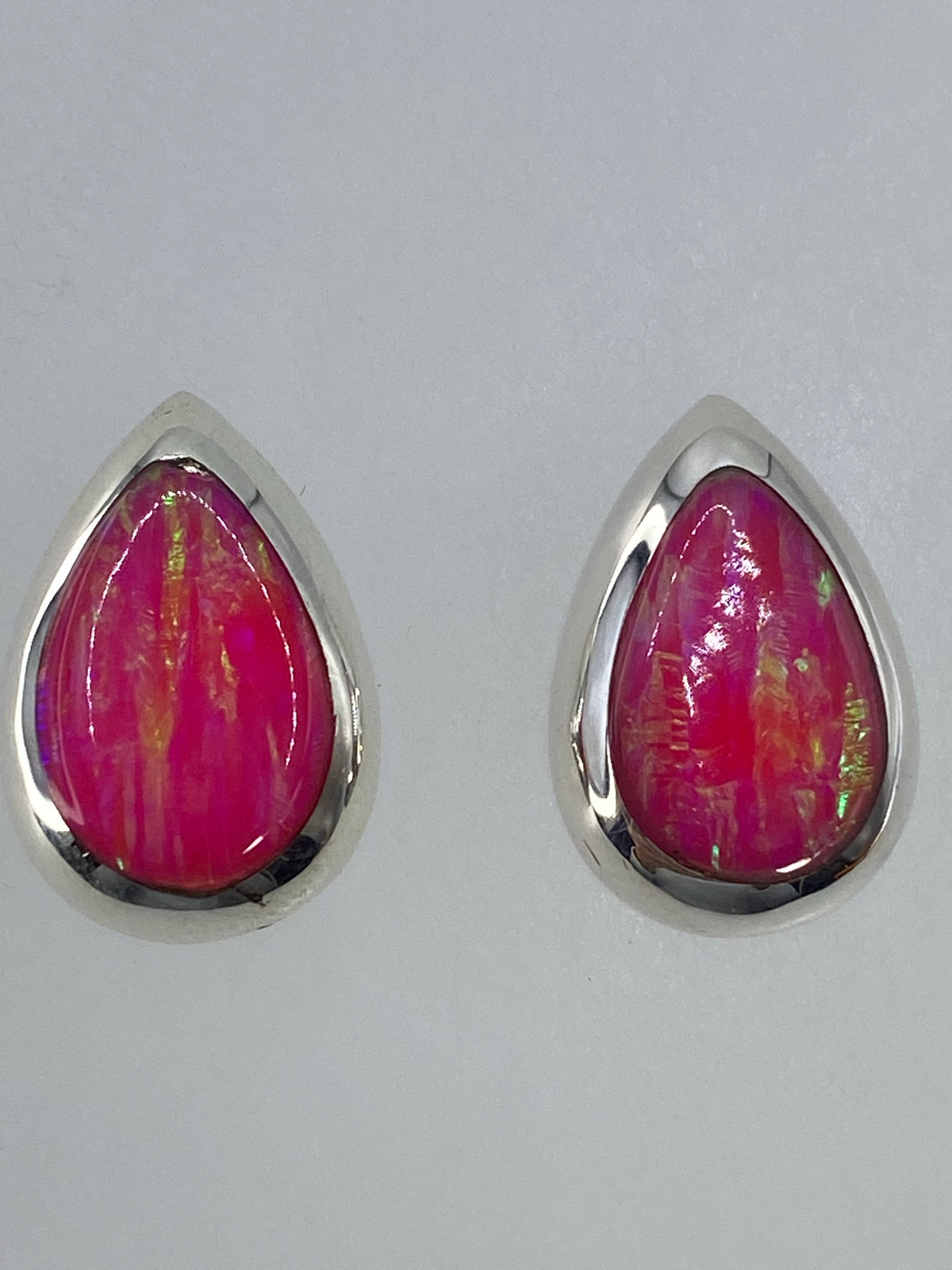 Aretes de ópalo de fuego mostrando el juego de luz verde en ambas piedras