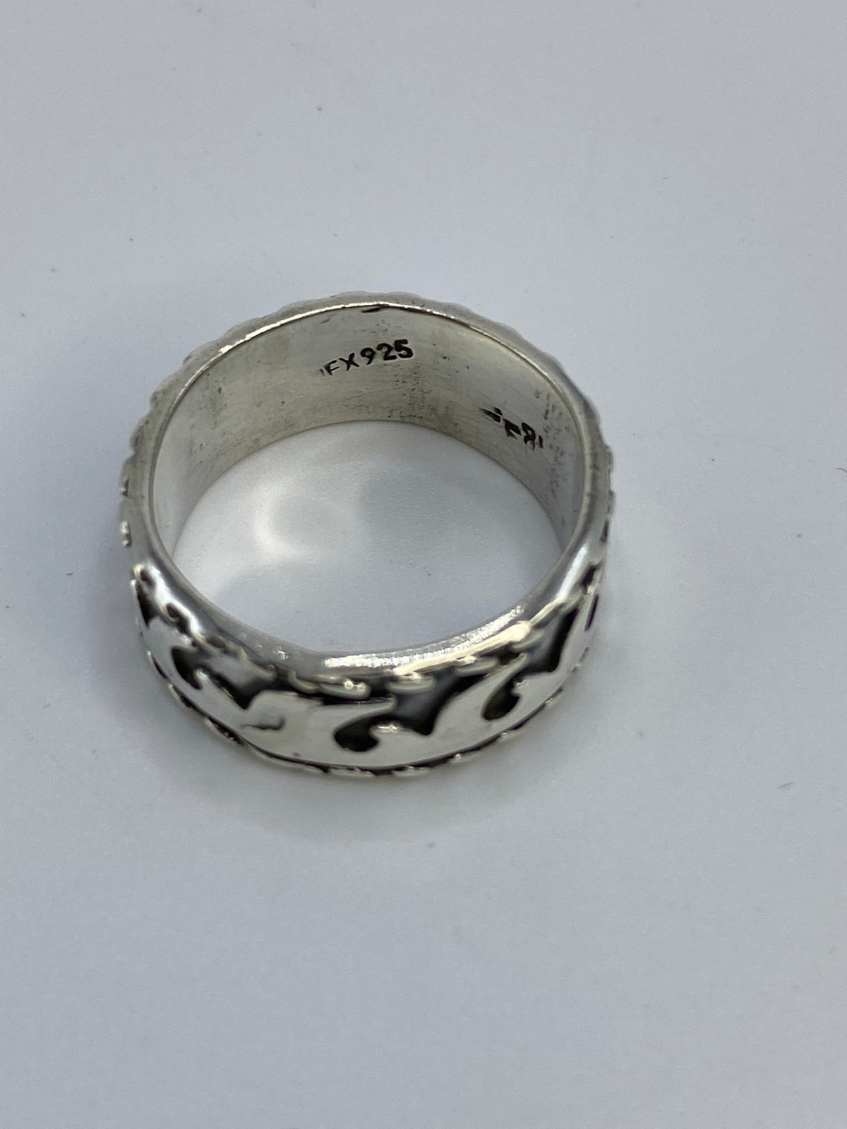Anillo sobre fondo azul exhibiendo el acabado satinado y la geometría fluida