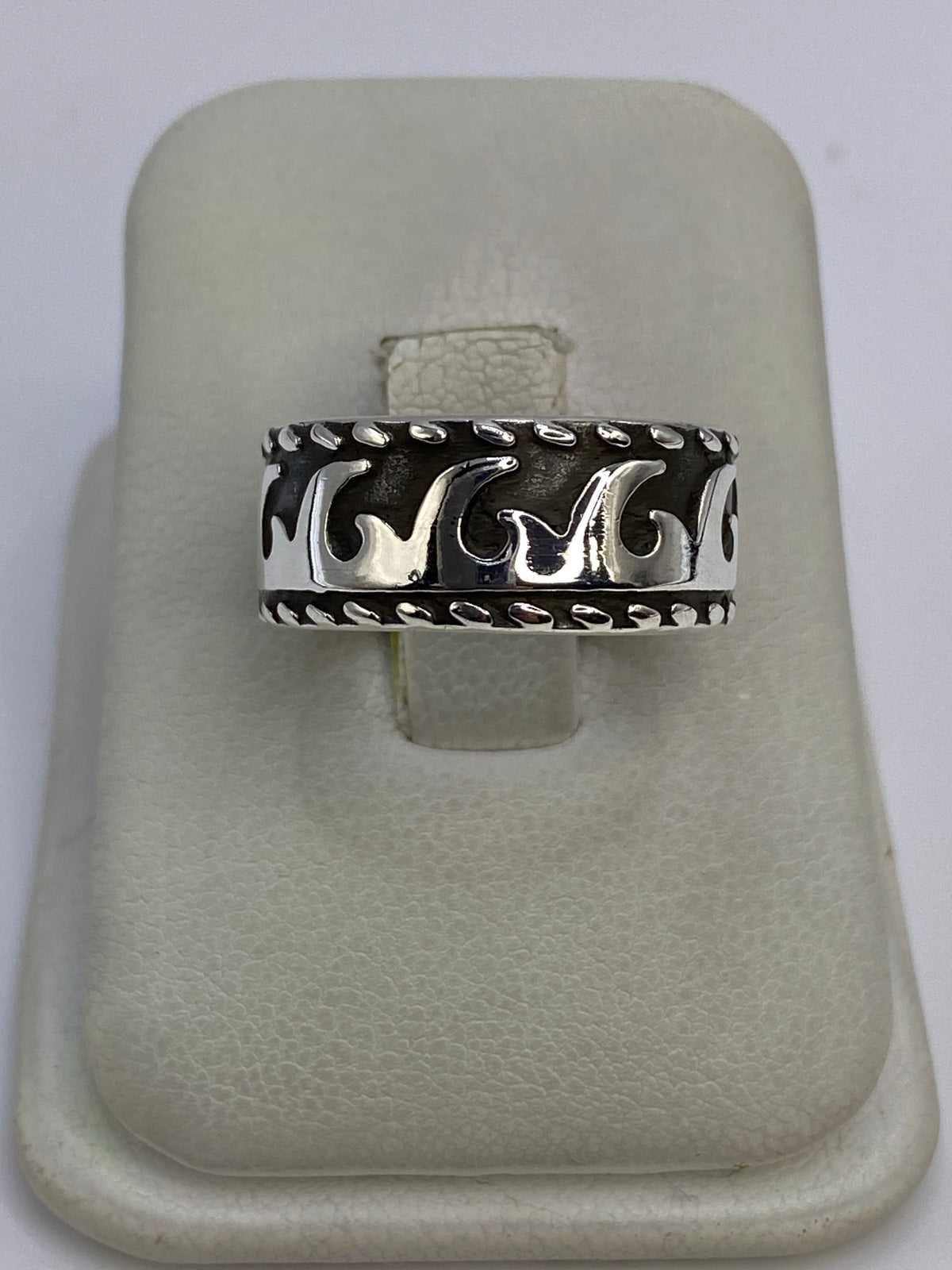 Anillo de plata repujado con motivo de olas, visto de frente sobre dedo