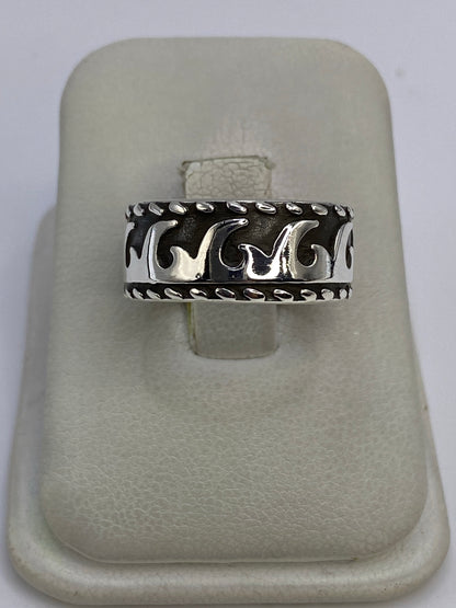 Anillo de plata repujado con motivo de olas, visto de frente sobre dedo