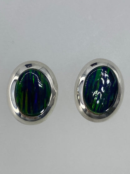 Aretes de plata con ópalo de fuego verde, visto de frente mostrando la luminosidad de la piedra