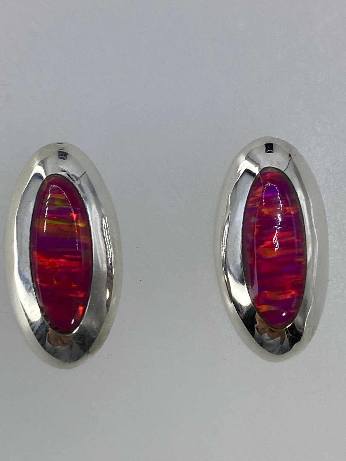 Par de aretes de plata con ópalo de fuego rosa, vista frontal mostrando el brillo de la piedra