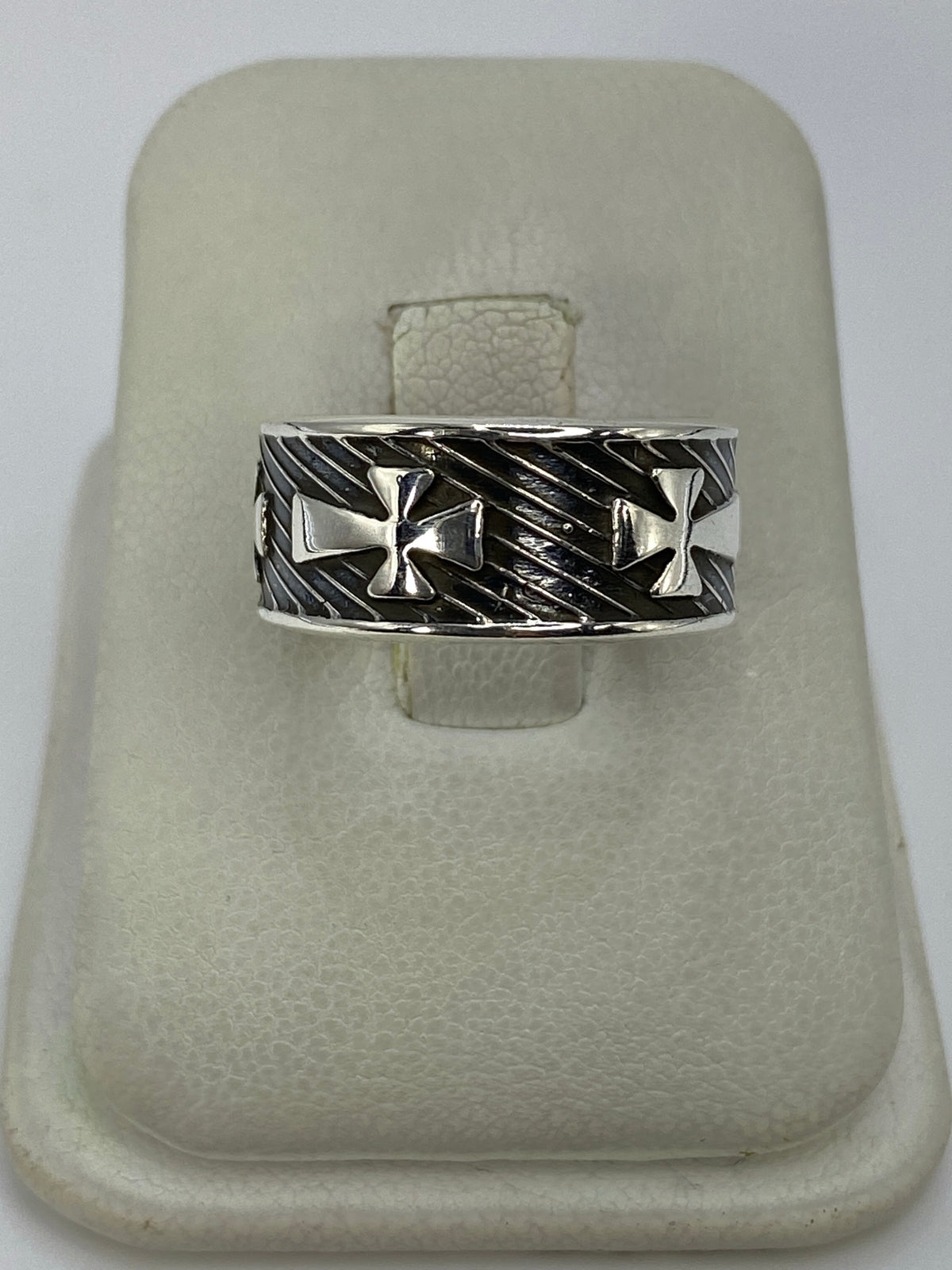 Anillo de plata repujado con cruces en relieve sobre estuche blanco