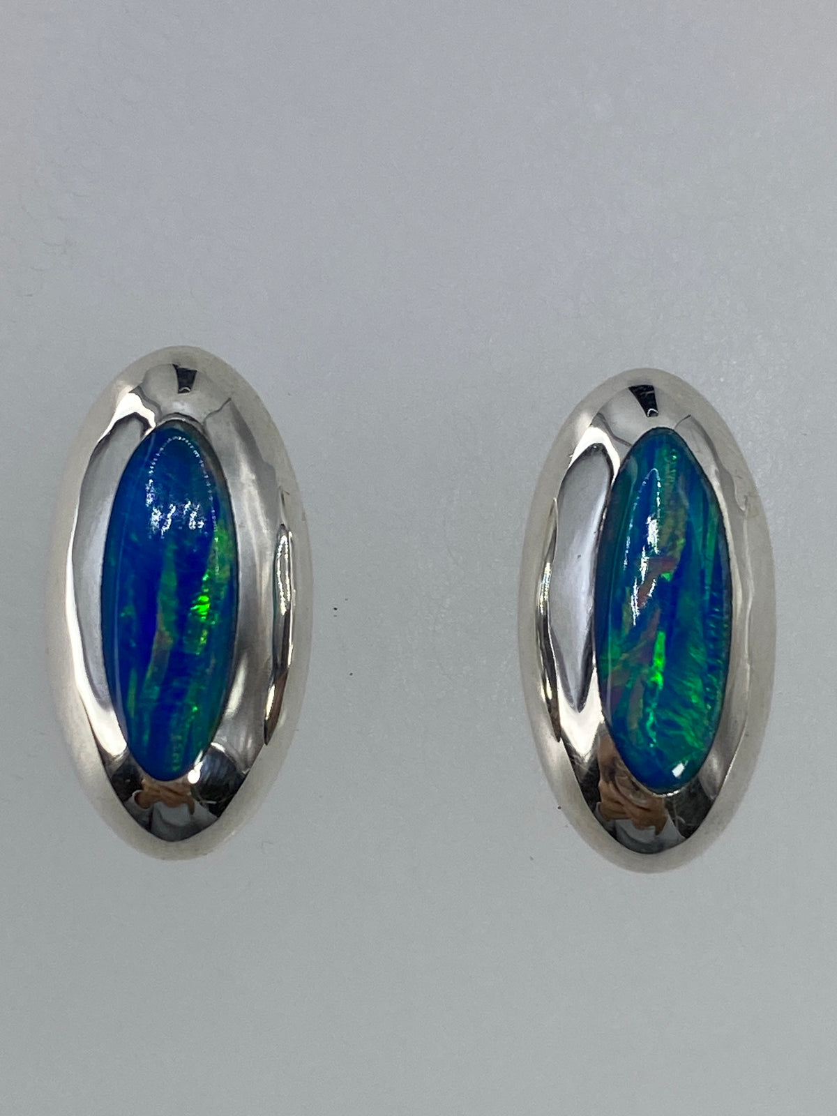 Par de aretes de plata con ópalo de fuego verde limón, brillando bajo la luz