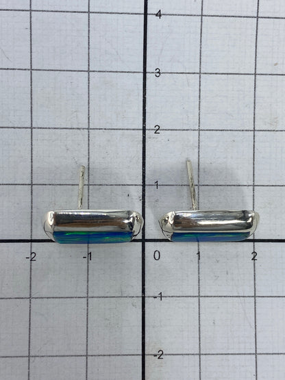 Medida comparativa de los aretes de 1.4 cm sobre regla de centímetros, con el Quinto 925 en la parte trasera