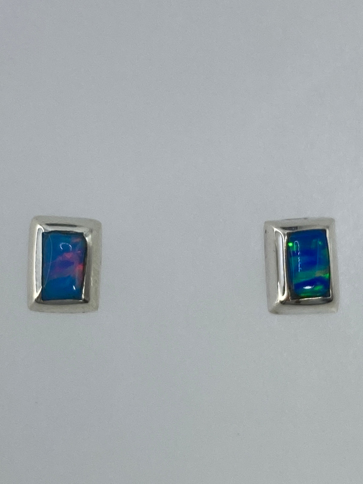 Aretes de plata 925 con ópalo de fuego multicolor, vistos en par sobre fondo blanco