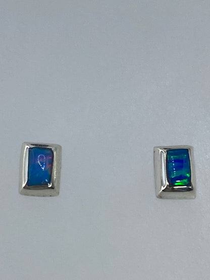 Aretes de plata del lado, evidenciando el delicado poste y el color multicolor de la piedra