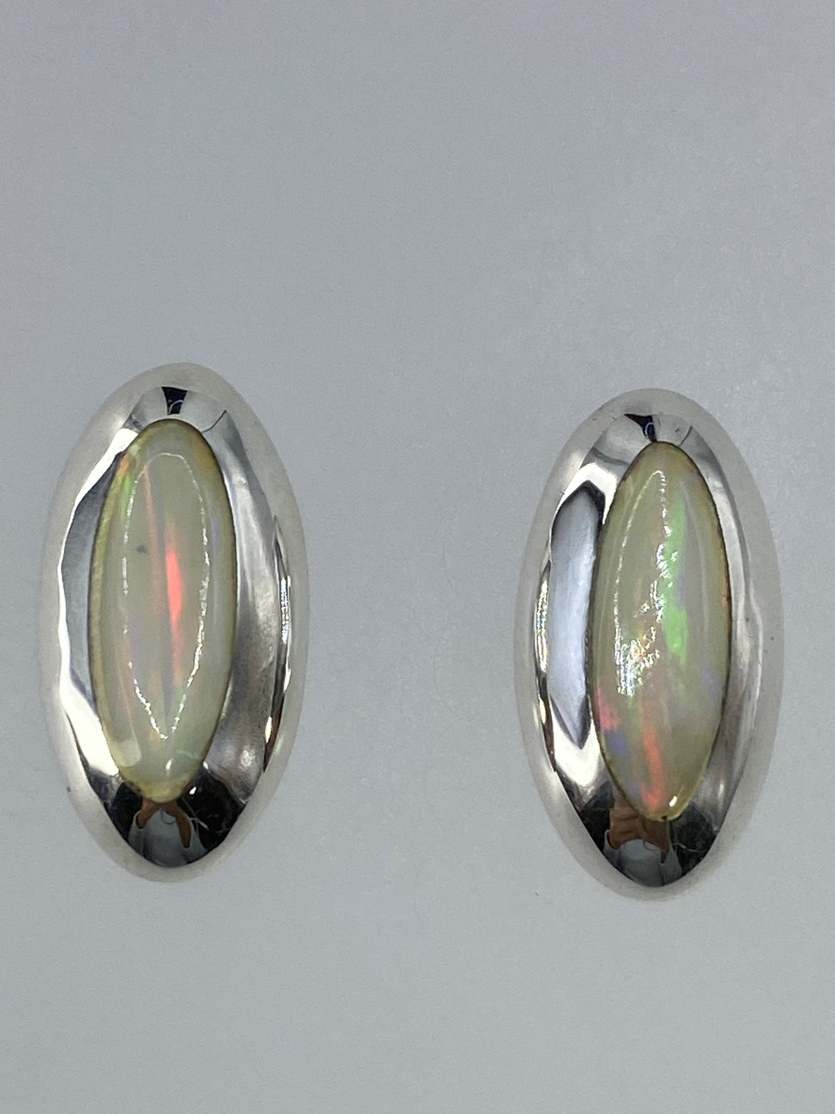 Par de aretes de plata con Ópalo de Fuego multicolor, mostrando los reflejos de rojo y verde