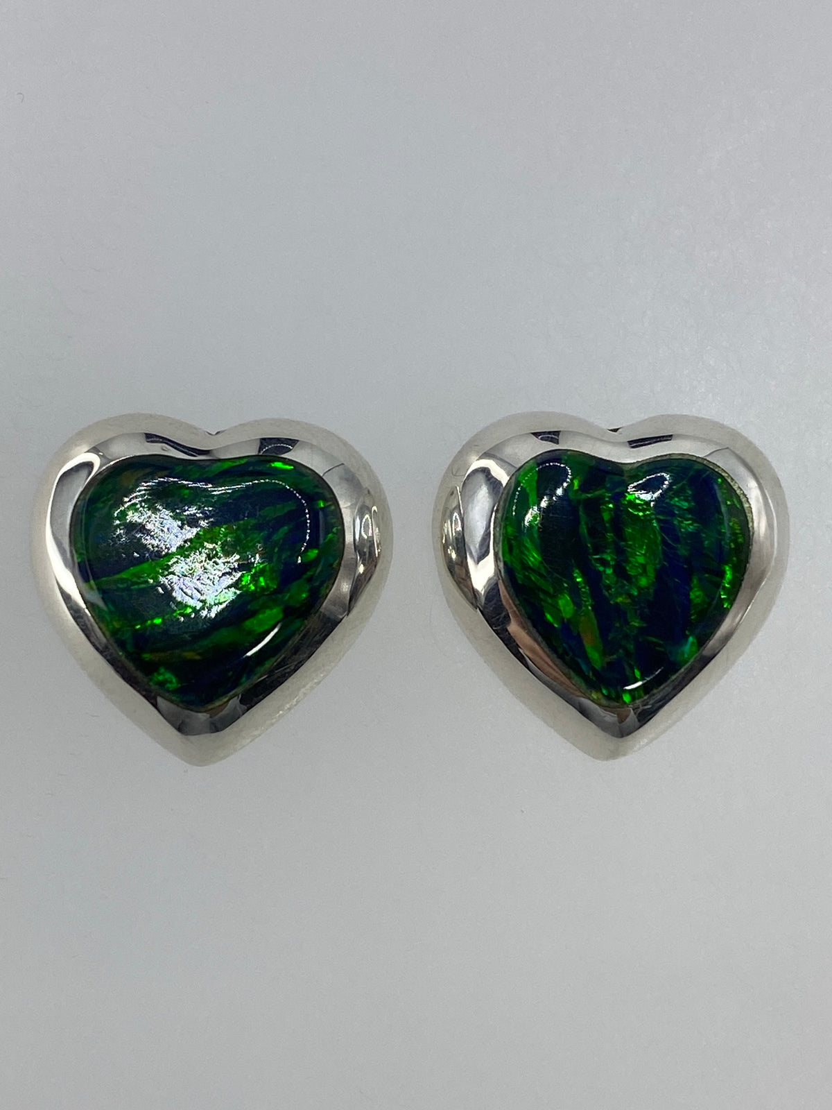 Aretes sostenidos en escala de medida mostrando tamaño real de 1.4 cm