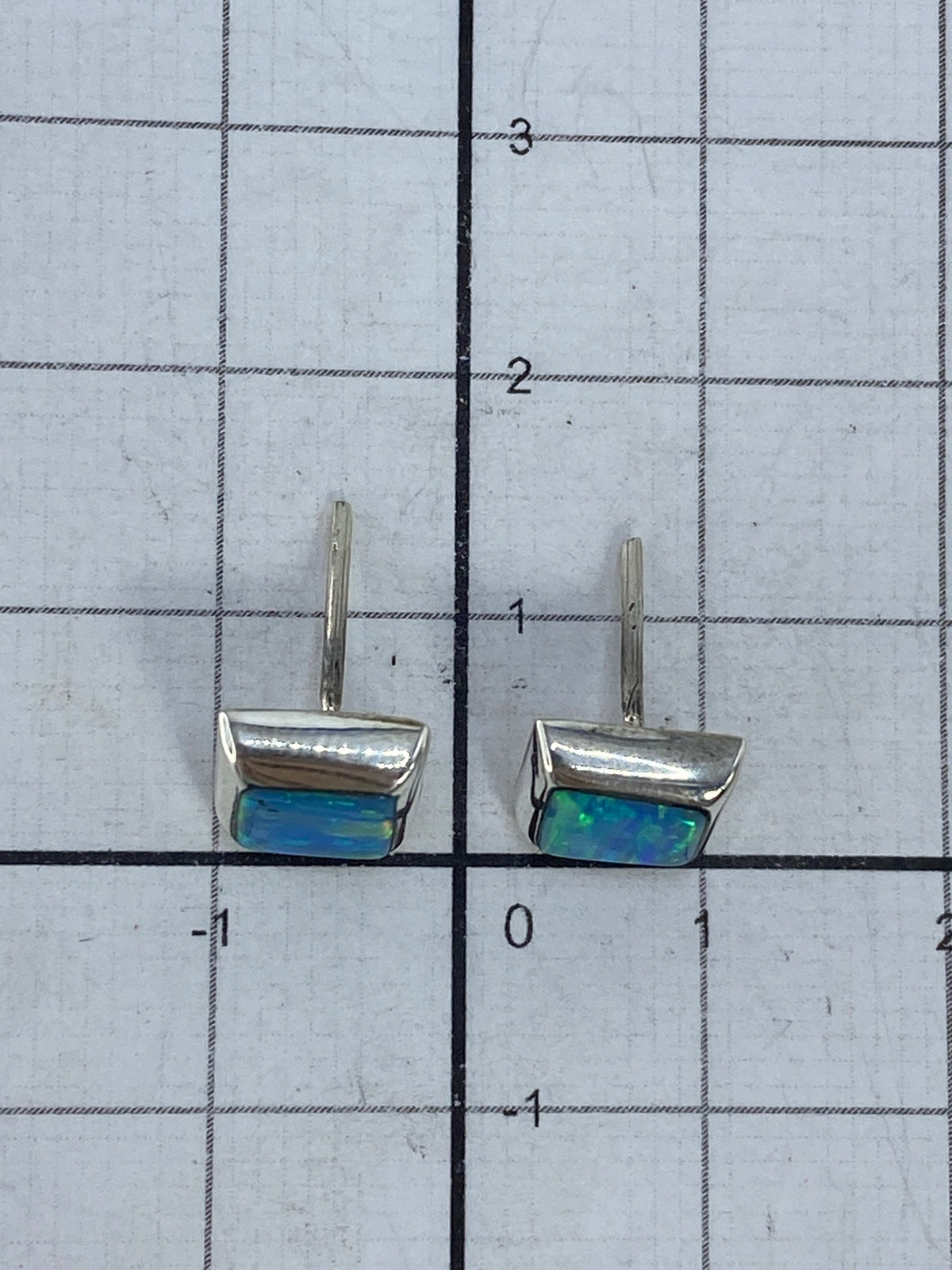 Vista frontal de los aretes: opalo brillante en contraste con plata pulida