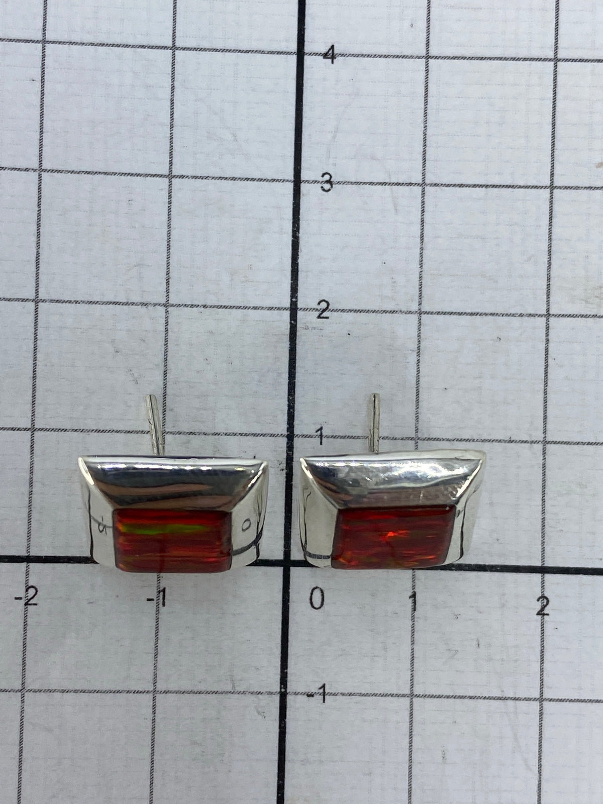 Aretes de ópalo de fuego sobre superficie blanca con marca 925