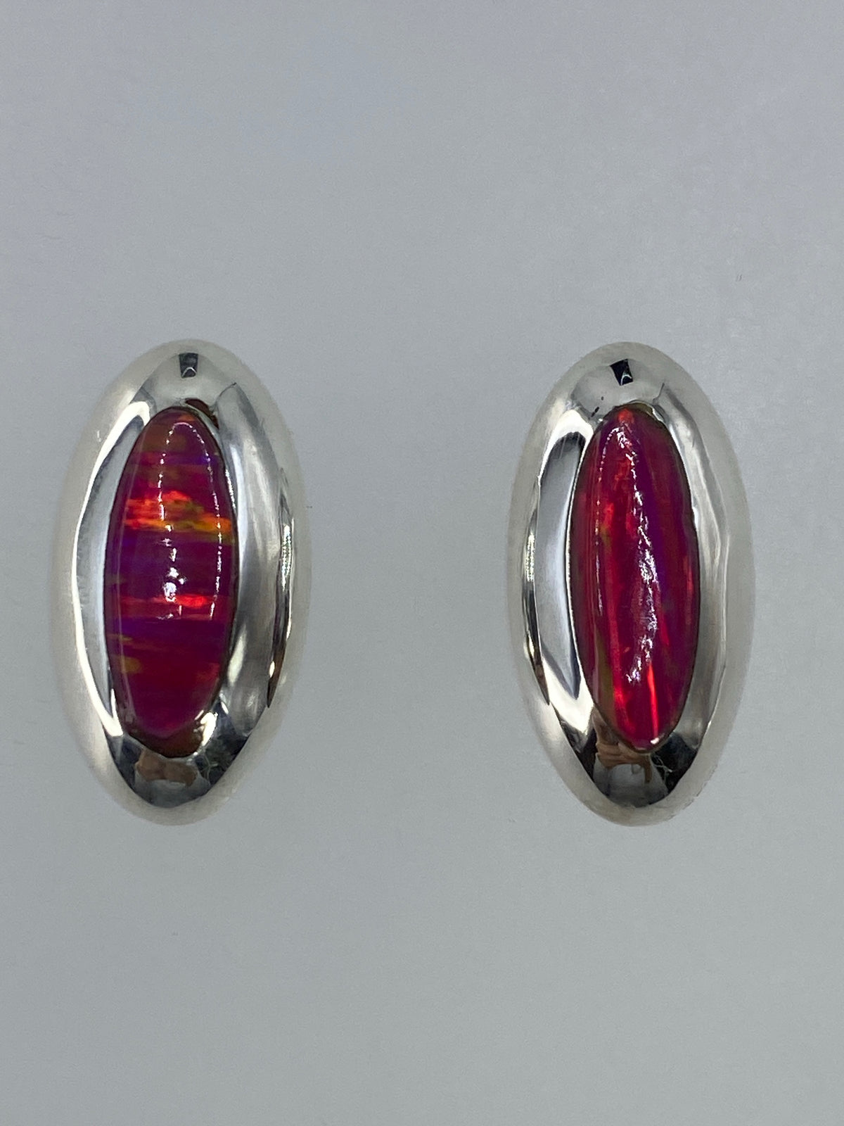 Par de aretes de plata 925 con ópalo de fuego rosa, luz frontal mostrando el brillo coral-anaranjado