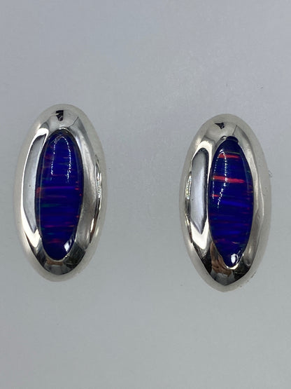 Detalle frontal de arete de ópalo de fuego con tonos rojos y naranjas