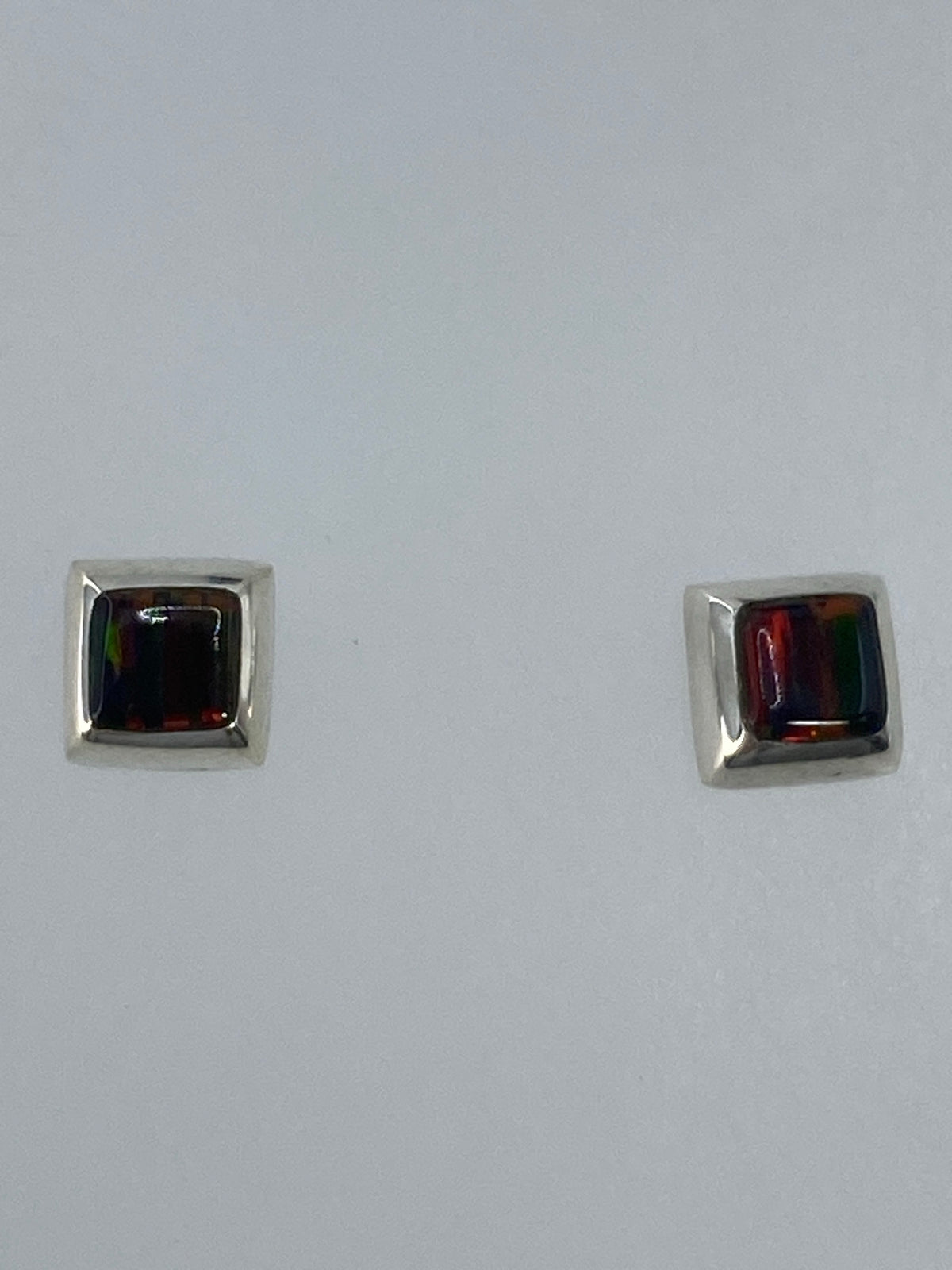 Detalle frontal de los aretes mostrando el color multicolor del ópalo de fuego
