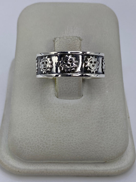 Anillo de plata repujado con calaveras prehispánicas en talla 7, mostrado en dedo pulgar