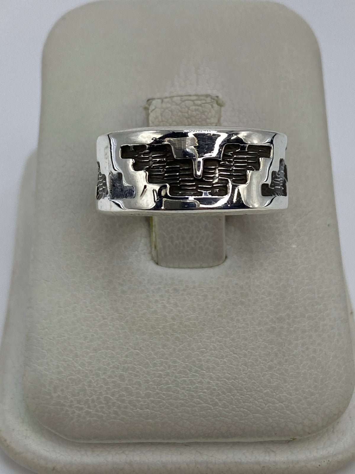 Anillo de plata repujado con diseño geométrico prehispánico en la mano de una persona